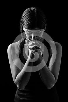 Faithful athletic woman praying, with hands folded in worship to god