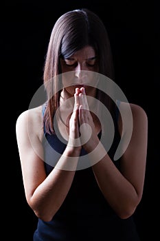 Faithful athletic woman praying, with hands folded in worship to god