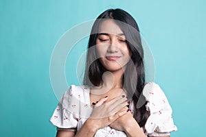 Faithful woman closes eyes and keeps hands on chest near heart, shows her kindness