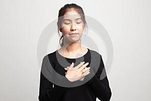 Faithful woman closes eyes and keeps hands on chest near heart, shows her kindness