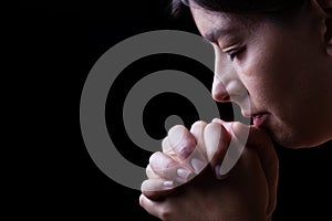 Faithful woman praying, hands folded in worship to god photo