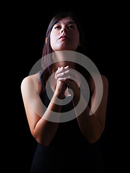 Faithful woman praying, hands folded in worship to god with looking up