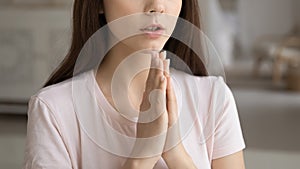 Faithful young woman keeping hands together in pray to god