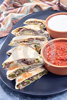 Fajita quesadilla with pieces of beef steak, green bell pepper, onion and cheese, on plate