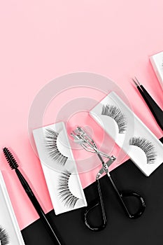 Fake eyelashes. Makeup accessories. Cosmetics. Tools for eye lash extensions on pink and black background. Vertical.