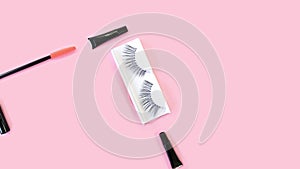 Fake eyelashes. Tools for eye lash extensions on pink background. Eyelash curler, tweezers, brushes. Makeup accessories.