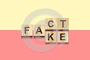 Fake, Fact. The inscription on wooden blocks on a yellow, red background.