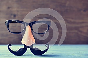 Fake mustache, nose and eyeglasses on a blue surface