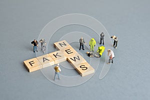 Fake news concept - figurines investigating scrabble pieces