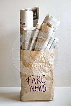 Fake news concept : a paper bag filled with newspapers and the word Fake News on it