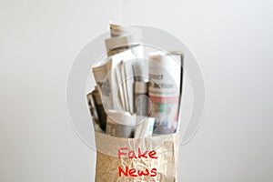 Fake news concept :  a paper bag filled with newspapers and the word Fake News on it