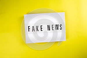 Fake News text on lightbox on yellow background isolated. vintage billboard