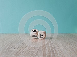 Fake or true symbol. Businessman flips a wooden cube and changes the word \'fake\' to \'true\' or vice versa