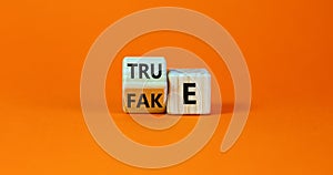 Fake or true symbol. Turned a wooden cube and changed the word `fake` to `true` or vice versa. Beautiful orange table, orange