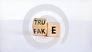 Fake or true symbol. Turned a wooden cube and changed the word `fake` to `true` or vice versa. Beautiful white table, white