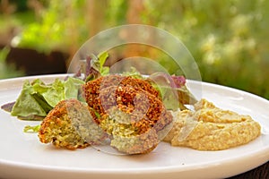 falafel balls, one cut, humus and salad on a plate, selective focus