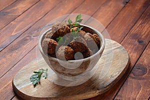 Falafel balls with parsley in wooden bowl with tahini sauce.