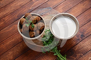 Falafel balls with parsley in wooden bowl with tahini sauce.