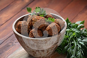 Falafel balls with parsley in wooden bowl with tahini sauce.