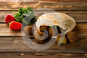 Falafel balls, pita-arabian bread and fresh vegetables on a wooden background.