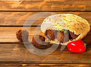 Falafel balls, pita-arabian bread and fresh vegetables on a wooden background.
