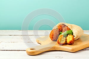 Falafel balls served with pita and lettuce on a wooden board