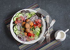 Falafel and fresh vegetables salad on dark background, top view. Vegetarian, diet food