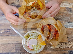 Falafel in Pita and salad, man`s hands.