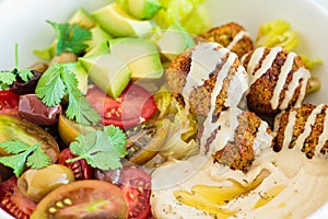 Falafel plate with salad, tomatoes, avocado, hummus and olives