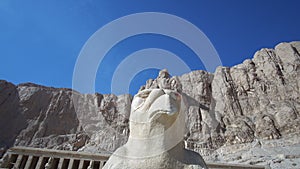 Falcon horus statue in front of Mortuary Temple of Hatshepsut in Luxor Egypt low angle sky and cliff