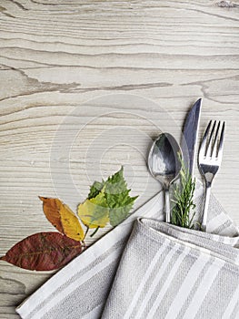 Fall or autumn themed place setting with a knife, spoon and fork, napkin on a plate on an arrangement of colorful leaves, copy