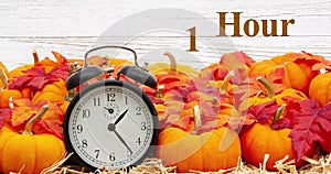 Fall Back 1 hour time change message with a retro alarm clock with pumpkins and fall leaves