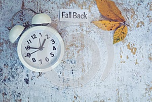 Fall Back Daylight Saving Time concept with white clock and flowers, flat lay