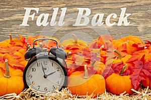 Fall Back time change message with a retro alarm clock with pumpkins and fall leaves