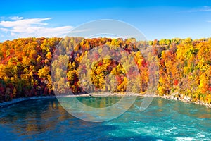 Fall background. Landscape during day light. Autumn trees on the river bank. Mountains and forest. Vivid colours in the forest.