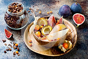 Fall breakfast bowl with chocolate granola, coconut yogurt and autumn seasonal fruits and berries. Healthy vegetarian breakfast