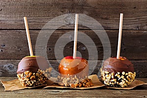 Fall candy apples with chocolate and caramel, side view against dark wood