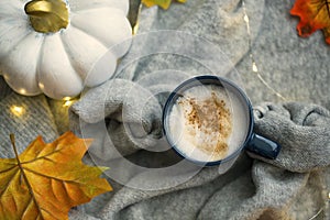 Fall coffee cup with cinnamon on cozy soft sweather, top view, autumn leaves and pumpkin decorations