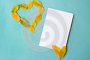 Fall colorful yellow leaves of heart frame paper on blue paper background