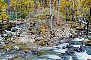 Fall colors surround a small white water stream in fall.