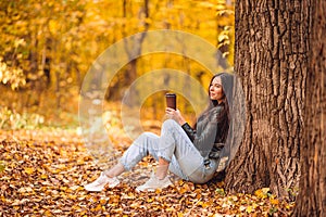 Fall concept - beautiful woman in autumn park under fall foliage