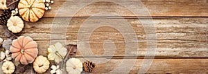 Fall corner border of pumpkins and natural decor over a rustic wood banner background