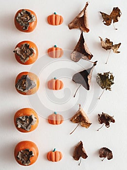 Fall flatlay with persimmons, pumpkin candies and dry leaves