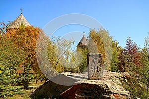 Fall foliage in the church courtyard with the ancient khachkar or Armenian cross-stone