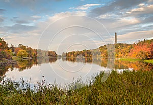 Fall foliage surrounds Lake Marcia as High Point Veteran`s Monument stands atop the mountain at sunset