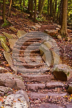 Fall forest hiking trail staircase lined with stone rocks winding up