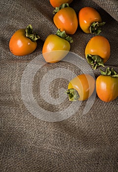 Fall Hachiya Persimmons in upper area in Rustic Still Life on Brown Burlap Fabric with blank room or space for copy, text or your