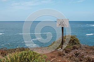 Fall hazard spanish: Peligro De Caidas warning sign with ocean photo