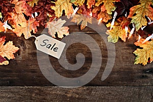 Fall Leaves and Sales Tag over Wooden Background