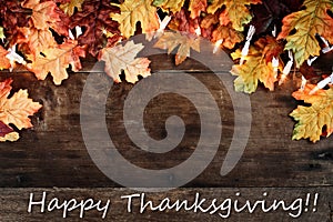 Fall Leaves and Text Happy Thanksgiving over Wooden Background